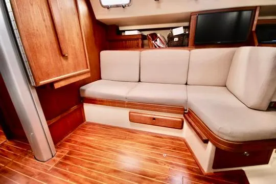 Solasta Yacht Photos Pics Interior of 1997 Island Packet 350 sailboat with wooden flooring and cushioned seating.