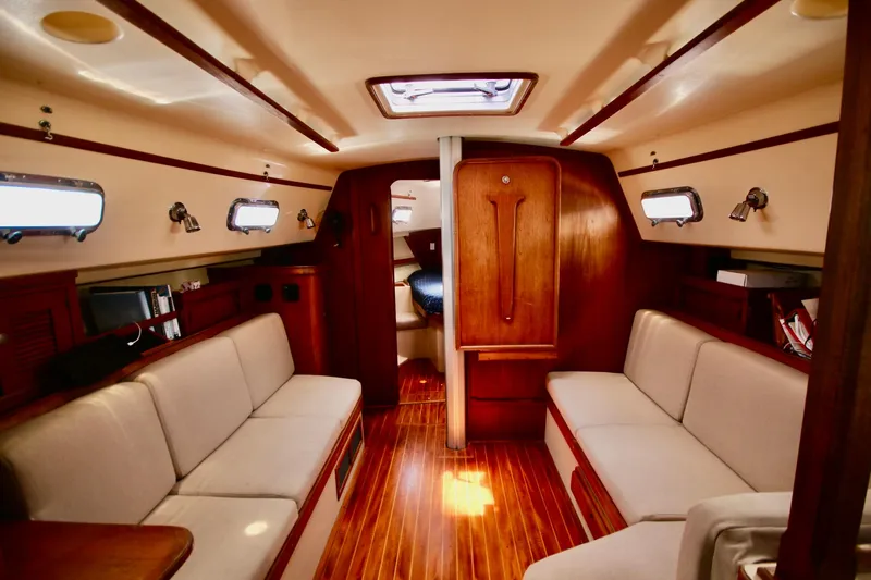 Solasta Yacht Photos Pics Interior of a 1997 Island Packet 350 sailboat with cozy seating and wooden finishes.