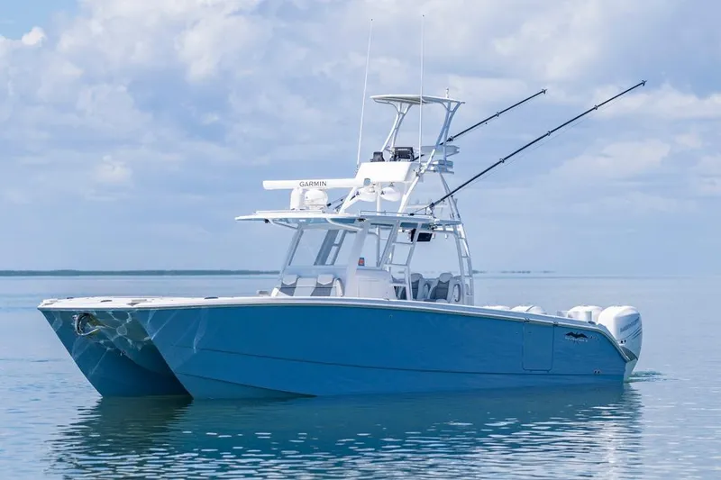  Yacht Photos Pics 2023 Invincible 37 Catamaran on calm water, featuring sleek design and fishing equipment.
