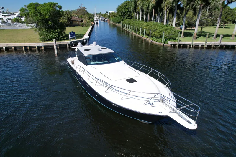  Yacht Photos Pics Uniesse 57 Open 1999 yacht cruising on a scenic waterway with lush greenery.