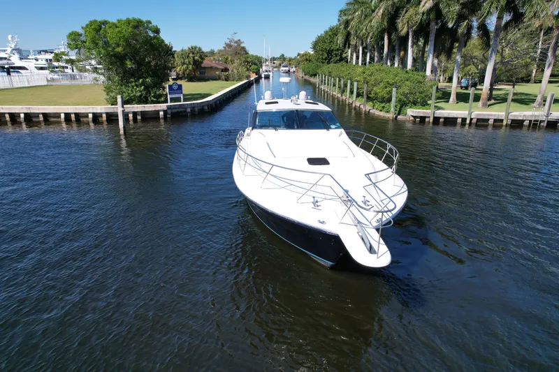  Yacht Photos Pics 1999 Uniesse 57 Open yacht cruising in a scenic canal with lush greenery.