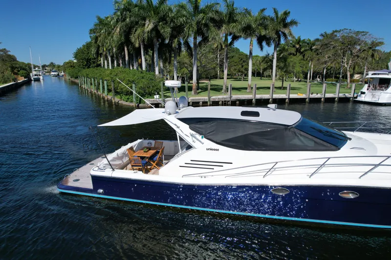  Yacht Photos Pics 1999 Uniesse 57 Open yacht cruising on a scenic waterway with palm trees.