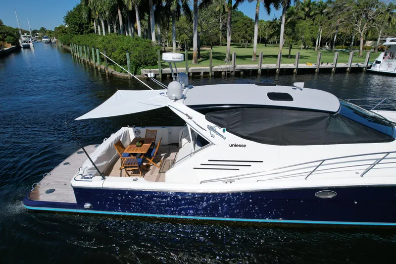  Yacht Photos Pics 1999 Uniesse 57 Open yacht cruising on a scenic waterway with lush greenery.