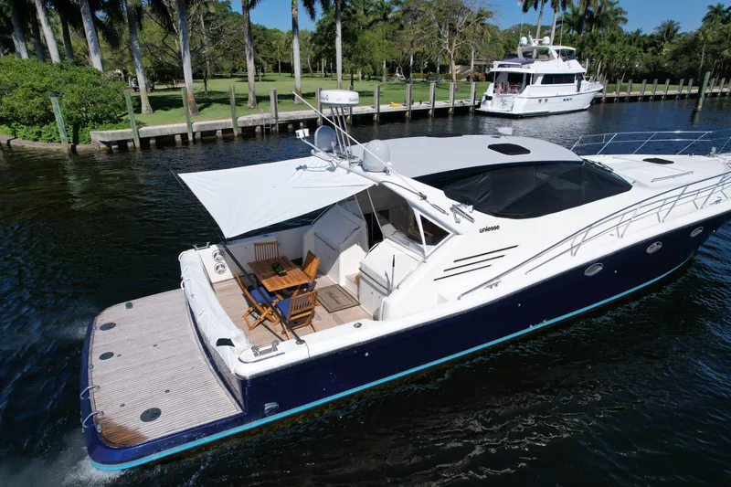  Yacht Photos Pics 1999 Uniesse 57 Open yacht cruising on a serene waterway, surrounded by lush greenery.