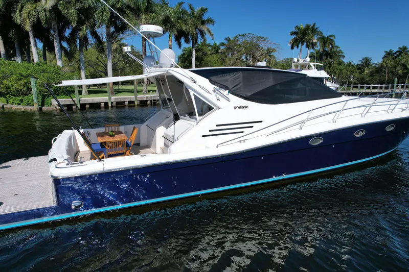  Yacht Photos Pics 1999 Uniesse 57 Open yacht docked on a sunny day, surrounded by palm trees.