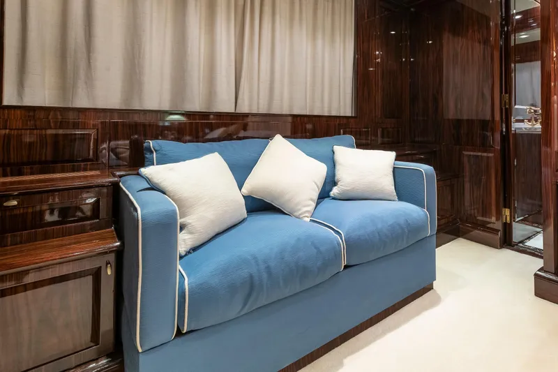 Claudia Berruto Yacht Photos Pics Luxurious interior of 2001 Baglietto M/Y 32 D yacht with blue sofa and wooden paneling.