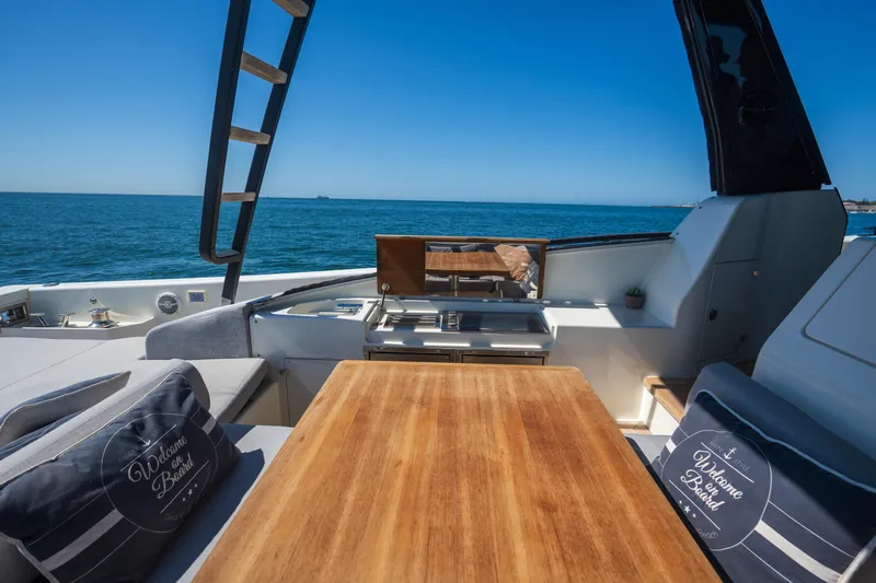  Yacht Photos Pics Luxurious 2019 Bluegame BG42 yacht deck with wooden table, ocean view, and comfortable seating.