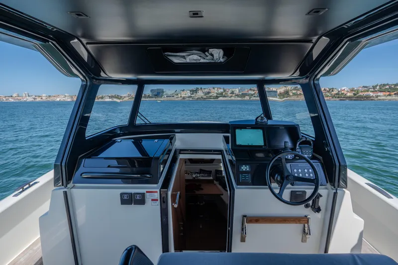  Yacht Photos Pics 2019 Bluegame BG42 yacht cockpit with navigation controls, overlooking calm sea and distant shoreline.