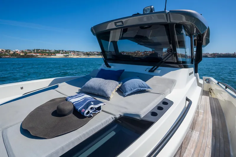  Yacht Photos Pics 2019 Bluegame BG42 yacht with sunbathing area, cushions, and hat on deck, cruising in clear waters.