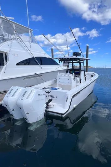  Yacht Photos Pics 2025 Reef Runner 280 boat docked, featuring dual engines and fishing rods under a blue sky.