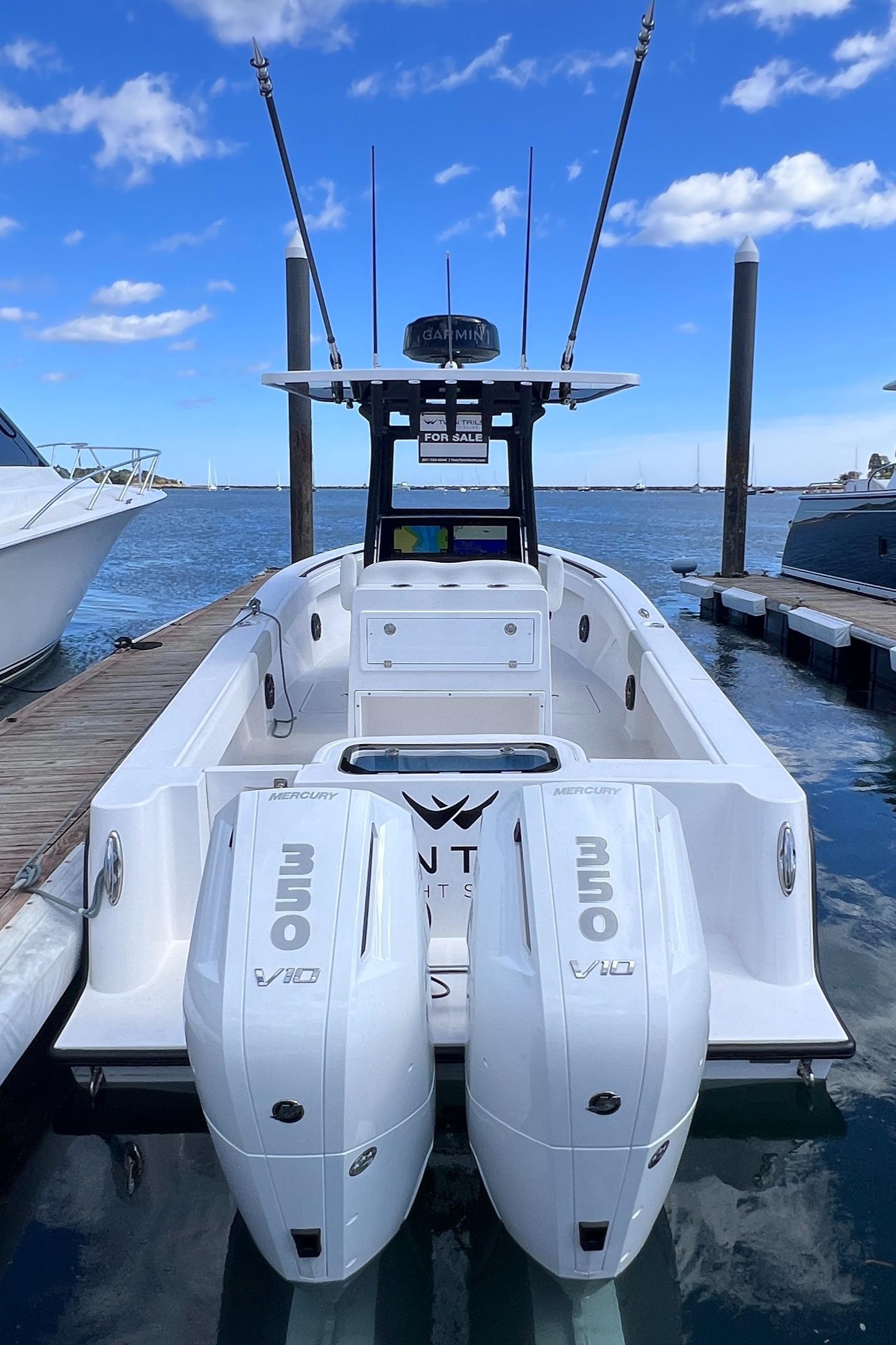 2025 Reef Runner 280 boat docked, featuring dual outboard engines under a clear blue sky.