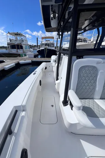  Yacht Photos Pics 2025 Reef Runner 280 boat docked, featuring sleek white design and comfortable seating.