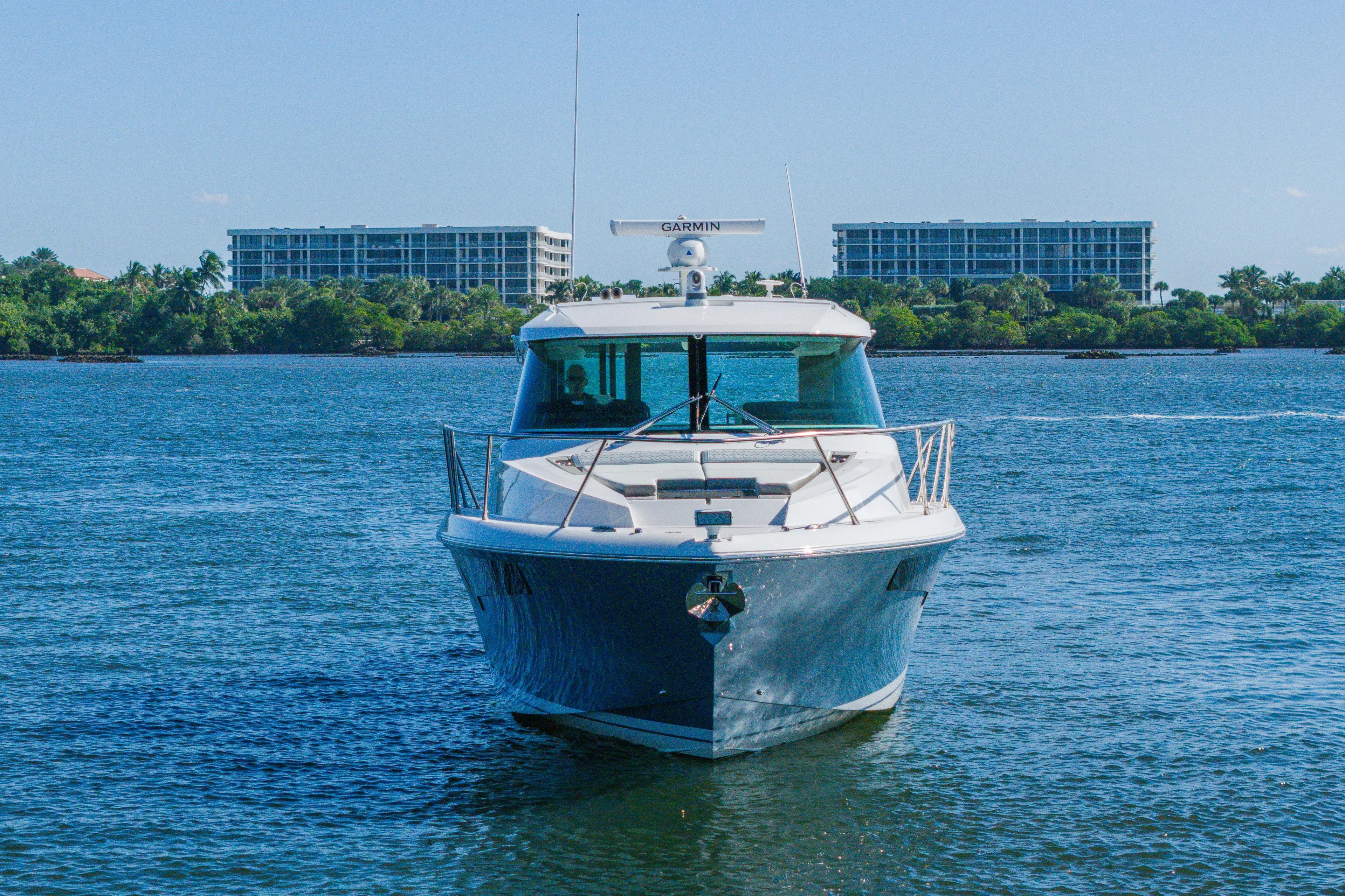 Next Level Yacht Photos Pics 2025 Tiara Yachts 43 LE cruising on a sunny day with buildings in the background.