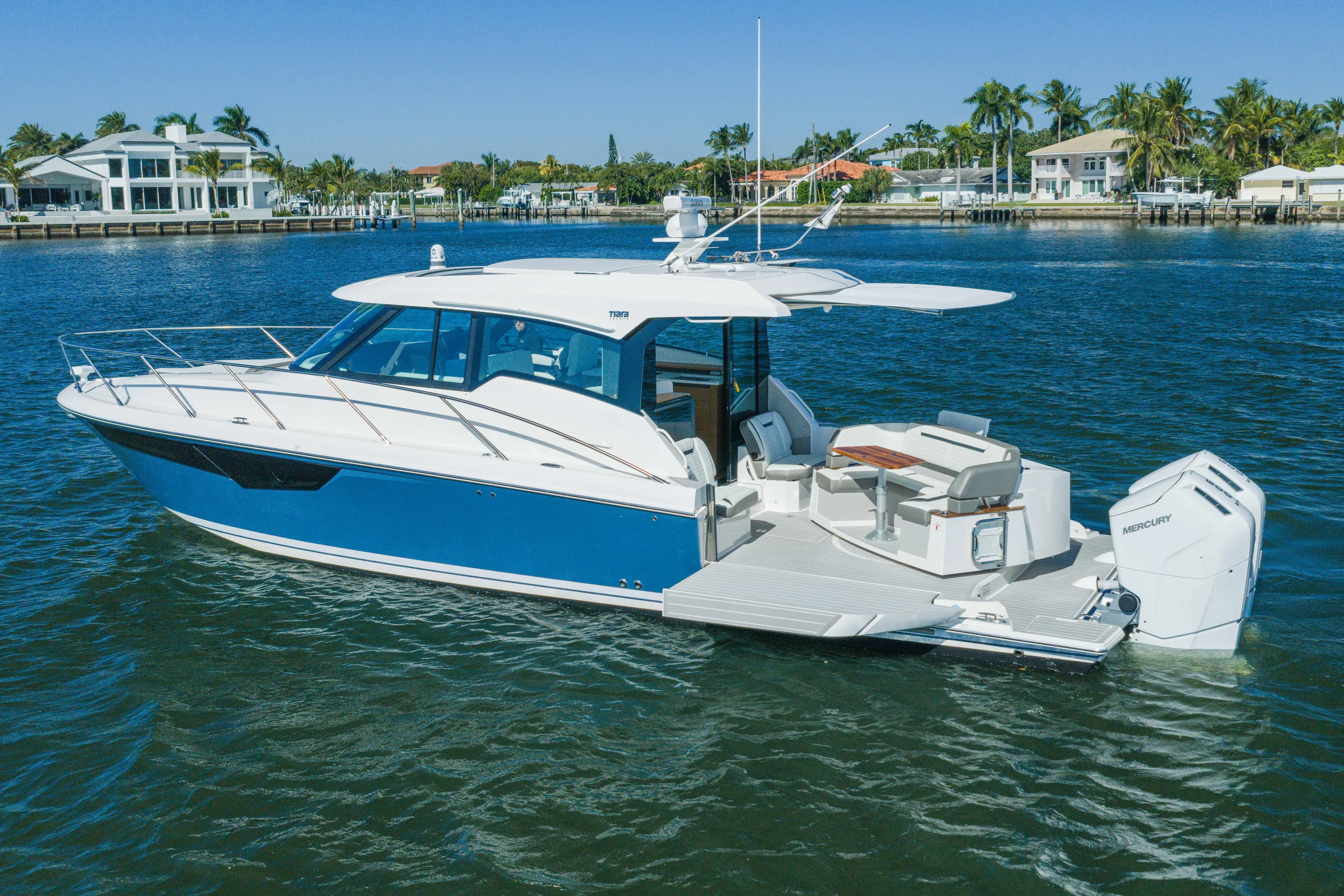 Next Level Yacht Photos Pics 2025 Tiara Yachts 43 LE cruising on a sunny day near waterfront homes.