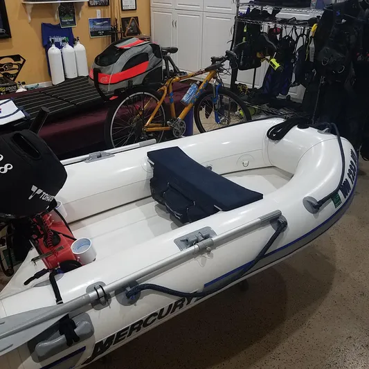  Yacht Photos Pics Inflatable boat with Mercury motor in a garage, alongside a bicycle and diving gear.