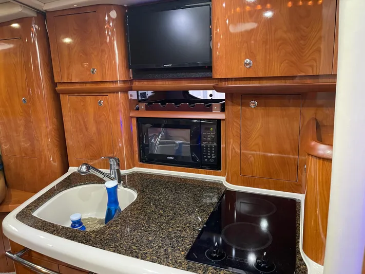  Yacht Photos Pics 2006 Four Winns 350 yacht kitchen with sink, stove, microwave, and TV.