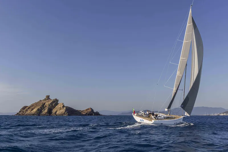  Yacht Photos Pics 2026 Grand Soleil 52 Performance sailing near rocky island under clear blue sky.