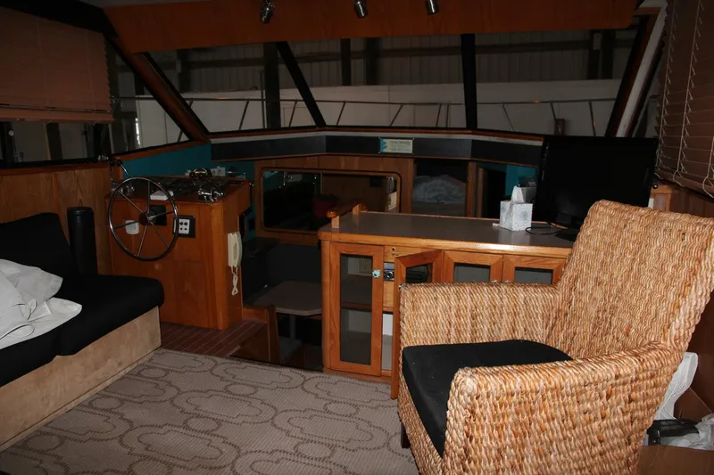 Aurora II Yacht Photos Pics Interior of 1989 Chris-Craft 480 Catalina yacht with wicker chair and wooden cabinetry.