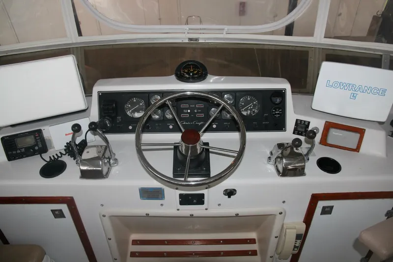 Aurora II Yacht Photos Pics 1989 Chris-Craft 480 Catalina helm with steering wheel, gauges, and navigation equipment.