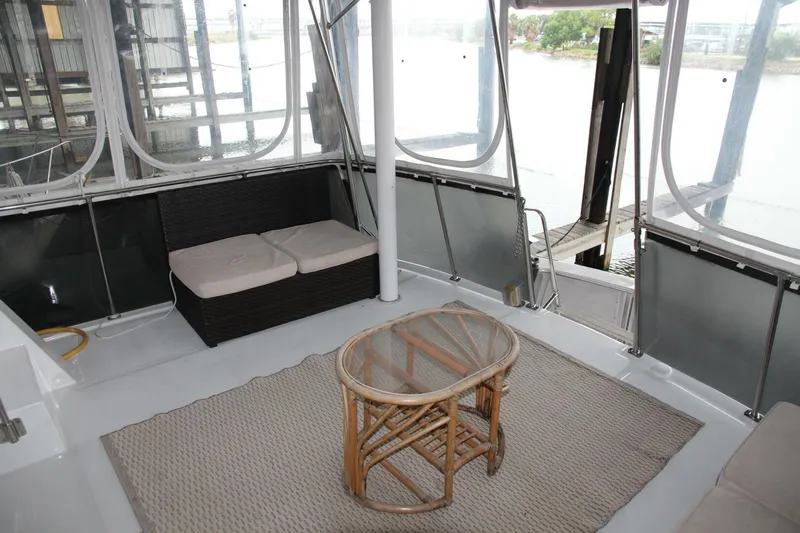 Aurora II Yacht Photos Pics 1989 Chris-Craft 480 Catalina yacht interior with wicker table and cushioned seating.