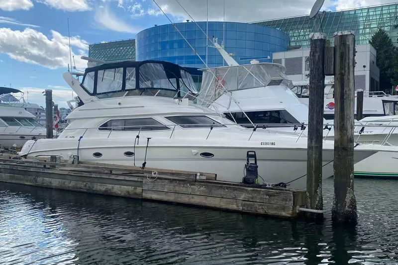 Oceanmax Yacht Photos Pics 2000 Sea Ray 450 Express Bridge yacht docked at marina with modern buildings.