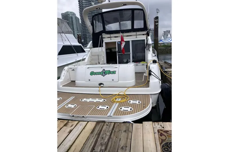 Oceanmax Yacht Photos Pics 2000 Sea Ray 450 Express Bridge docked, rear view with Canadian flag and cityscape background.