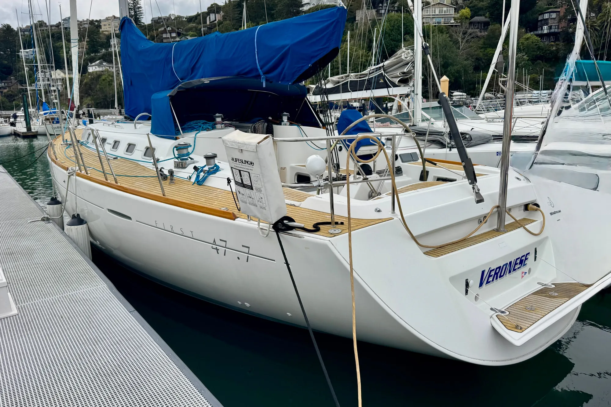 2003 Beneteau First 47.7 sailboat docked at marina, featuring sleek design and blue cover.
