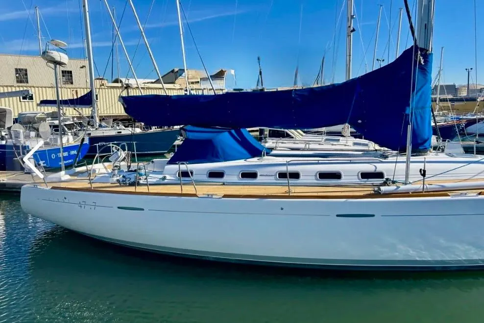 2003 Beneteau First 47.7 sailboat docked in marina, featuring blue sail covers.