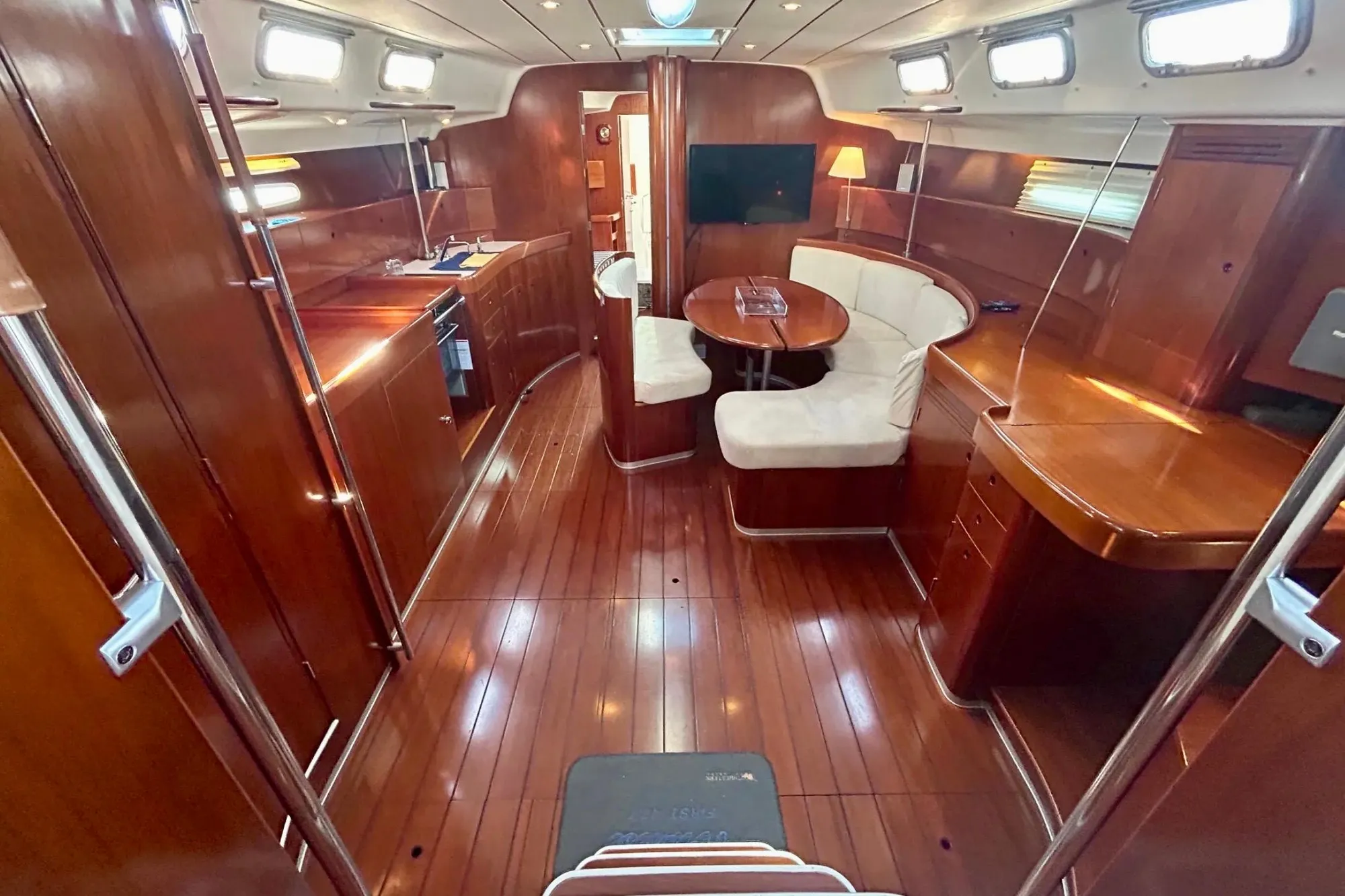 Luxurious interior of 2003 Beneteau First 47.7 yacht with polished wood and cozy seating.