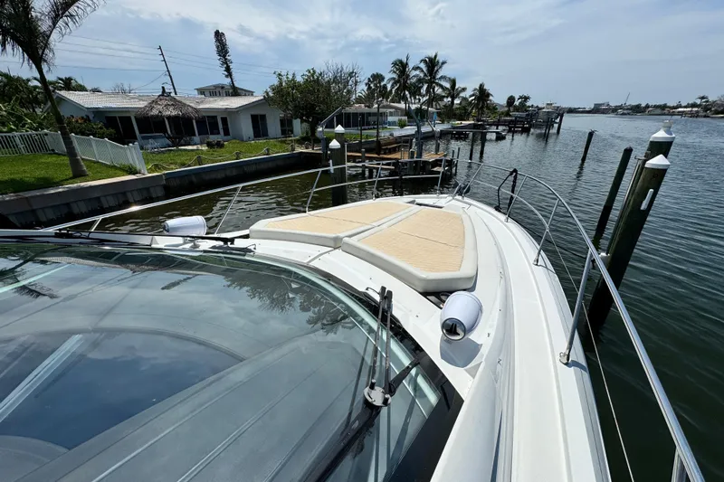  Yacht Photos Pics 2018 Beneteau Gran Turismo 46 yacht docked by waterfront homes, palm trees in background.