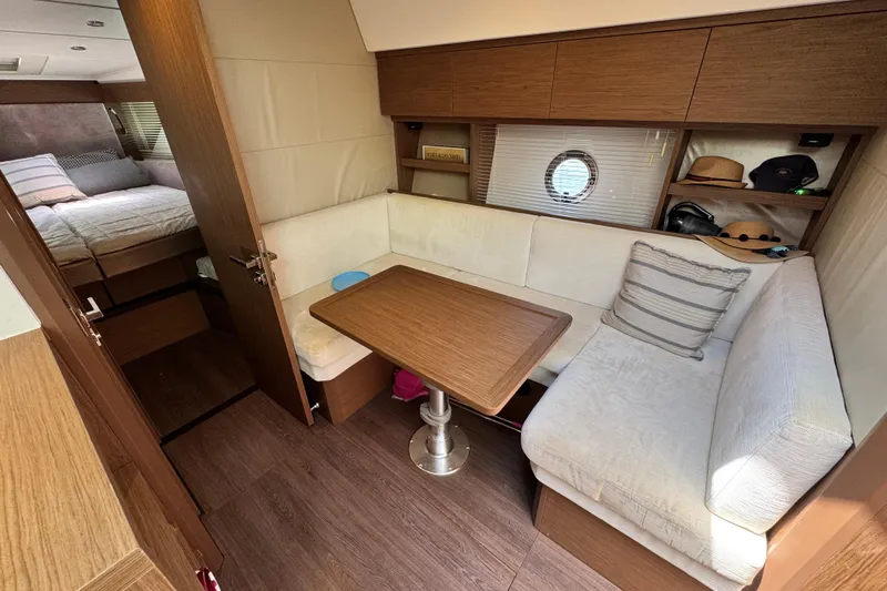  Yacht Photos Pics 2018 Beneteau Gran Turismo 46 interior with cozy seating, wooden table, and bedroom view.