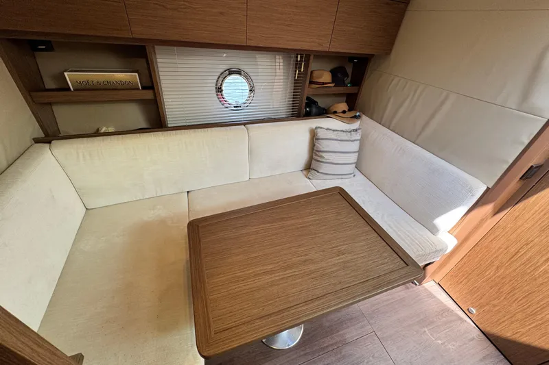  Yacht Photos Pics Interior of 2018 Beneteau Gran Turismo 46 yacht with cozy seating and wooden table.