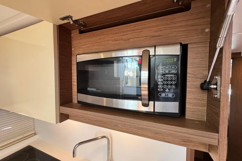  Yacht Photos Pics Microwave in 2018 Beneteau Gran Turismo 46 yacht kitchen, featuring modern wood cabinetry.