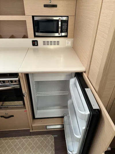  Yacht Photos Pics 2018 Jeanneau 51 yacht kitchen with open fridge, microwave, and oven.