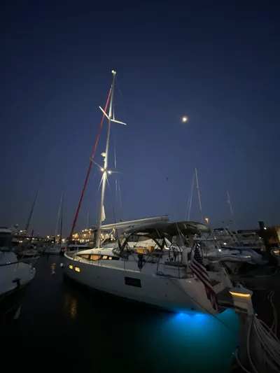  Yacht Photos Pics 2018 Jeanneau 51 sailboat docked at night, illuminated by blue underwater lights.