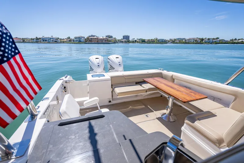 Kashmir Yacht Photos Pics 2019 Everglades 340 Dual Console boat with seating, table, and American flag on calm water.