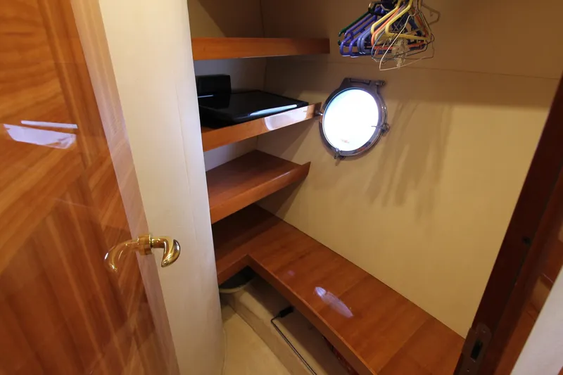 Sevrik Yacht Photos Pics Walk-in closet with wooden shelves and porthole on 2004 Azimut 62 yacht.