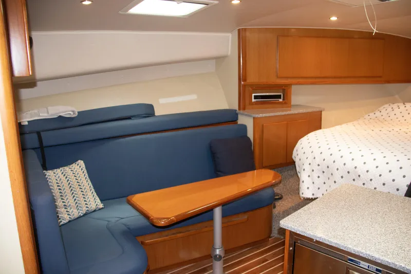 Peixe Espada Yacht Photos Pics 2016 Henriques 42 Express Hardtop interior with blue seating, wooden table, and cozy bed.