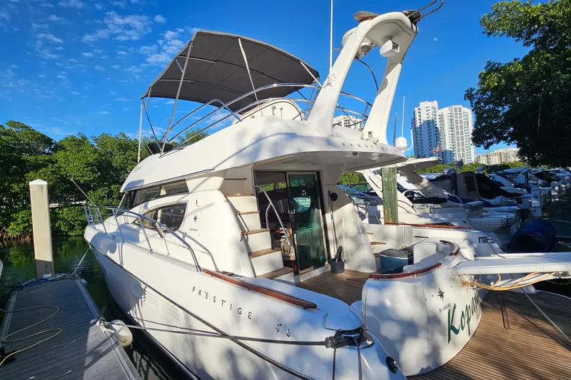 Kopara Yacht Photos Pics 2005 Prestige 46 yacht docked at marina, surrounded by trees and cityscape.