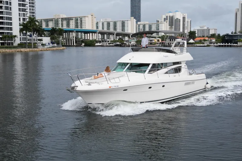 Kopara Yacht Photos Pics 2005 Prestige 46 yacht cruising in urban waterway with city skyline backdrop.
