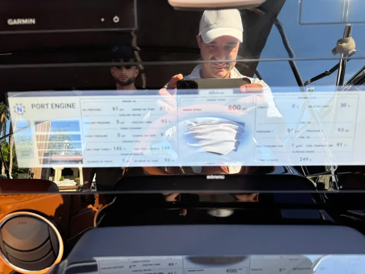 Grey Yacht Photos Pics Reflection on 2021 Riva 56 Rivale dashboard with engine display and two people.