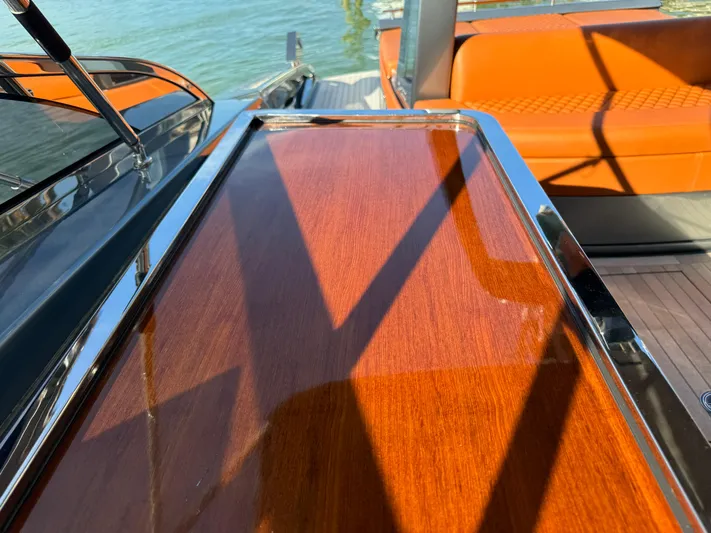 Grey Yacht Photos Pics 2021 Riva 56 Rivale yacht with polished wood and orange seating, docked by the water.