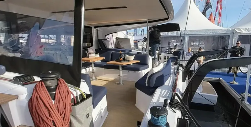 Good Wibe Yacht Photos Pics 2024 Nautitech 48 Open catamaran interior with seating and tables at a boat show.