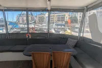 Cozy seating area on 2015 Flash Cat 52S yacht, with marina view through windows.