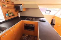 Modern kitchen in 2015 Flash Cat 52S yacht with stove, oven, and wooden cabinetry.