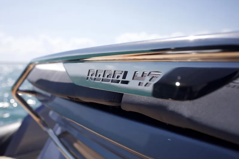  Yacht Photos Pics Close-up of 2022 SACS 47 Rebel boat nameplate with ocean background.