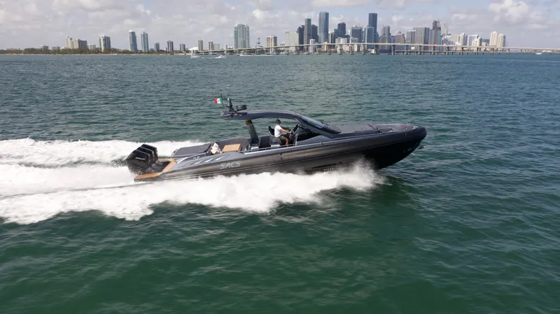  Yacht Photos Pics 2022 SACS 47 Rebel speedboat cruising on water with city skyline in background.