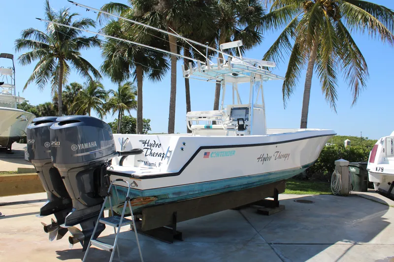  Yacht Photos Pics 2002 Contender 31 CC boat with dual Yamaha engines, docked under palm trees.