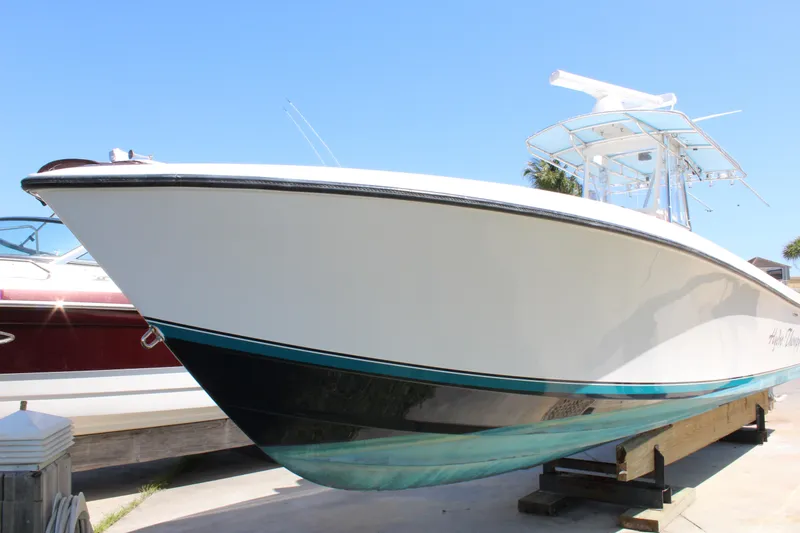 Yacht Photos Pics 2002 Contender 31 CC boat on display, white hull with teal accents, clear blue sky.