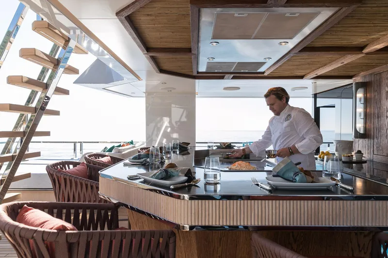 King Benji Yacht Photos Pics Luxurious 2024 Dunya Yachts Explorer kitchen with chef preparing gourmet meal.